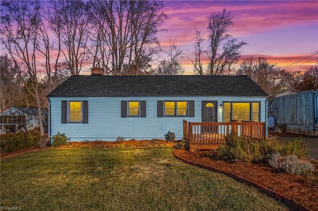 back house at dusk featuring a deck and a yard