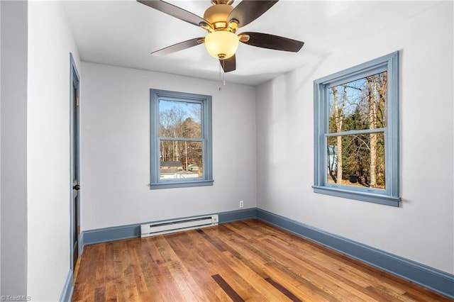 unfurnished room with ceiling fan, baseboard heating, and wood-type flooring