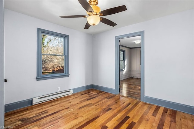 unfurnished room with ceiling fan, a baseboard radiator, and wood-type flooring