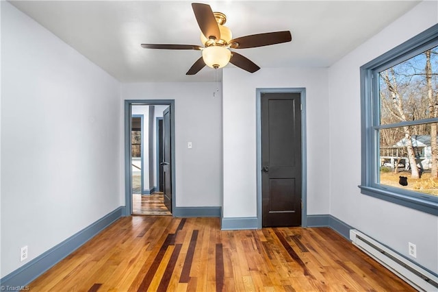 unfurnished bedroom with wood-type flooring, a baseboard radiator, and ceiling fan