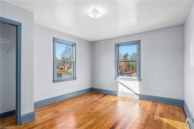 unfurnished bedroom featuring hardwood / wood-style flooring, a baseboard radiator, and a closet