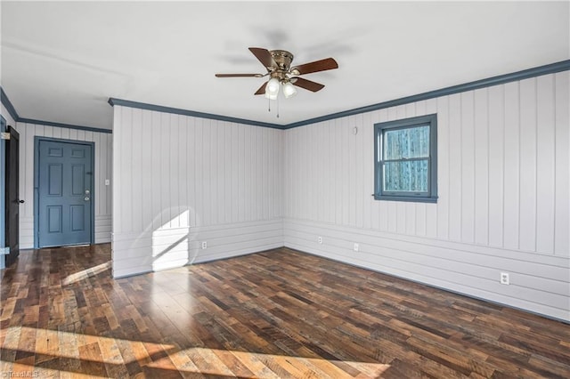 unfurnished room featuring crown molding, wood walls, dark hardwood / wood-style floors, and ceiling fan