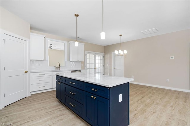 kitchen with light wood-style flooring, a chandelier, white cabinetry, and a kitchen island