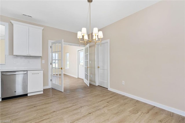 unfurnished dining area featuring french doors, light wood-type flooring, a chandelier, and visible vents