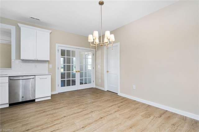 unfurnished dining area with light wood-type flooring, visible vents, a chandelier, french doors, and baseboards