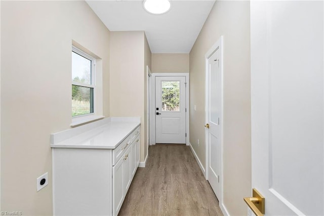 doorway to outside with light wood-style flooring and baseboards