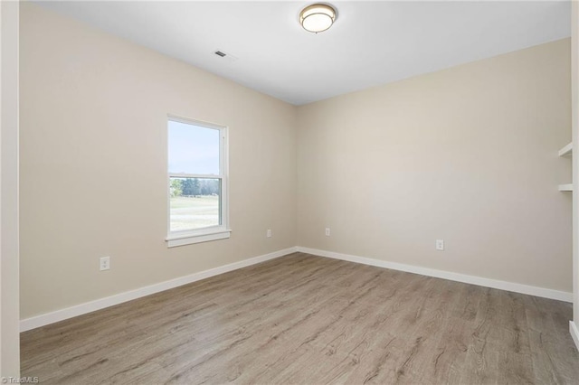 unfurnished room featuring visible vents, baseboards, and wood finished floors