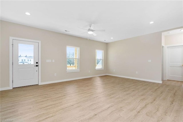 unfurnished living room with light wood-type flooring, ceiling fan, baseboards, and plenty of natural light