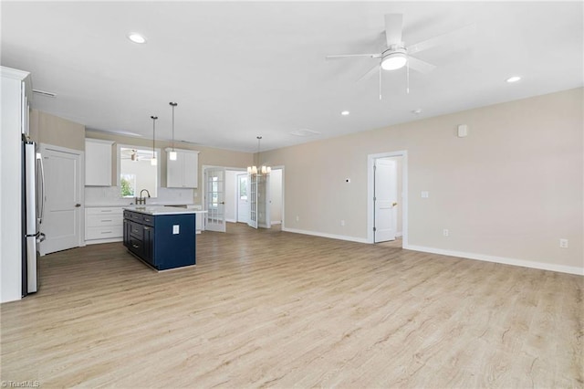 kitchen featuring open floor plan, light countertops, freestanding refrigerator, and light wood finished floors