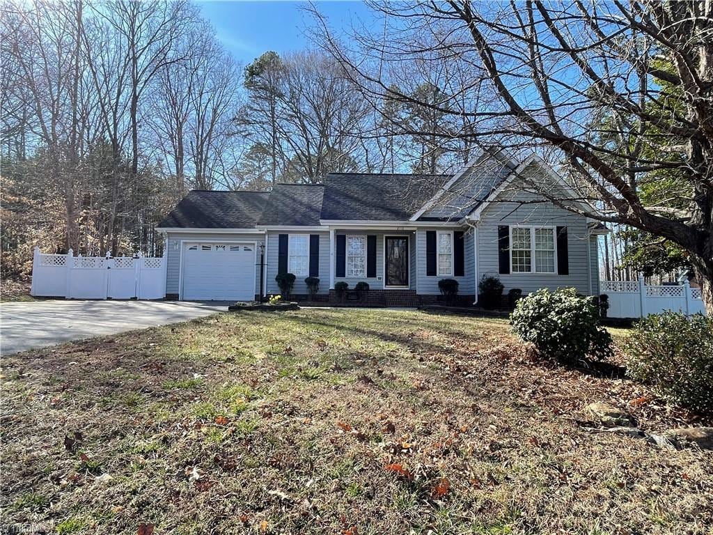 view of front of property with a garage, driveway, a front yard, and fence