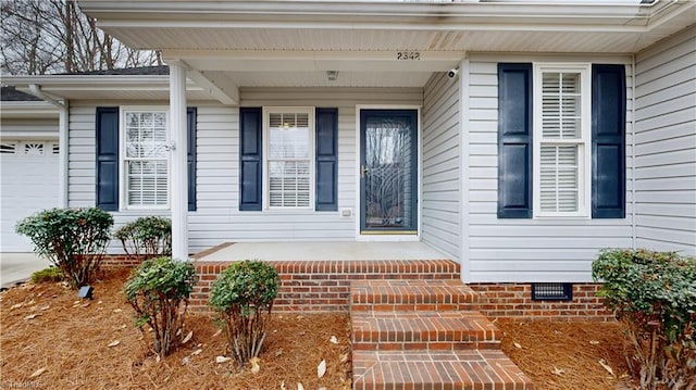 doorway to property featuring crawl space, an attached garage, and a porch