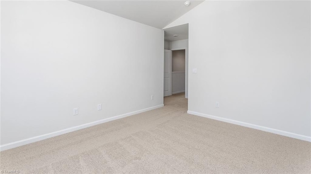 spare room with light colored carpet and vaulted ceiling