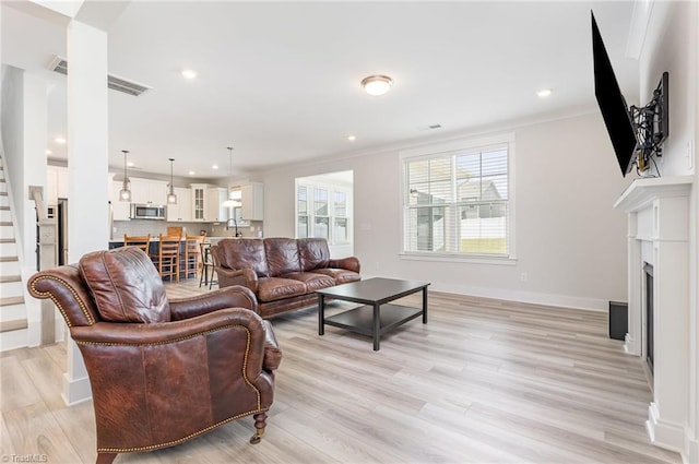 1515 Peabody Ct, Mebane, NC 27302 - living area featuring stairs, light wood-style floors, a fireplace, recessed lighting, and crown molding