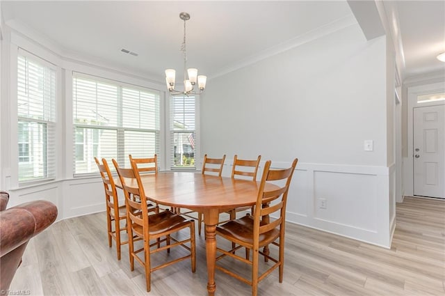 1515 Peabody Ct, Mebane, NC 27302 - dining room featuring a decorative wall, crown molding, a chandelier, light wood-style floors, and a wainscoted wall