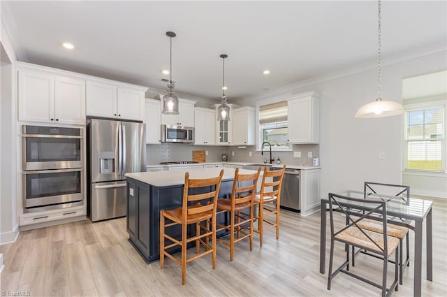 1515 Peabody Ct, Mebane, NC 27302 - kitchen with stainless steel appliances, light countertops, a center island, white cabinetry, and light wood finished floors