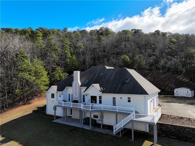 back of property featuring a wooden deck, a patio area, and a lawn