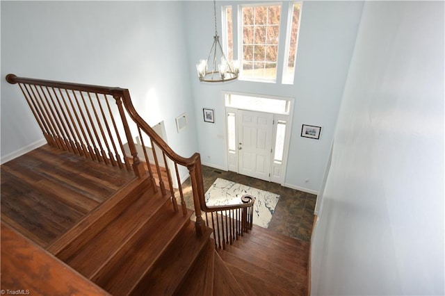 foyer with dark hardwood / wood-style flooring, a high ceiling, and an inviting chandelier