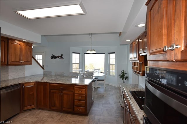 kitchen with appliances with stainless steel finishes, tasteful backsplash, a notable chandelier, light stone countertops, and kitchen peninsula