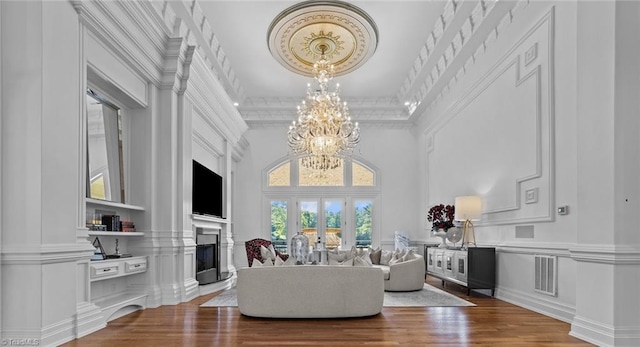 living room featuring ornamental molding, an inviting chandelier, wood-type flooring, and a high ceiling