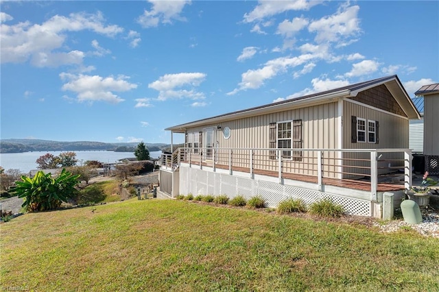 view of side of home with a yard and a deck with water view