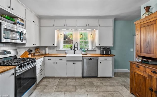 kitchen with appliances with stainless steel finishes, wood counters, backsplash, and white cabinetry