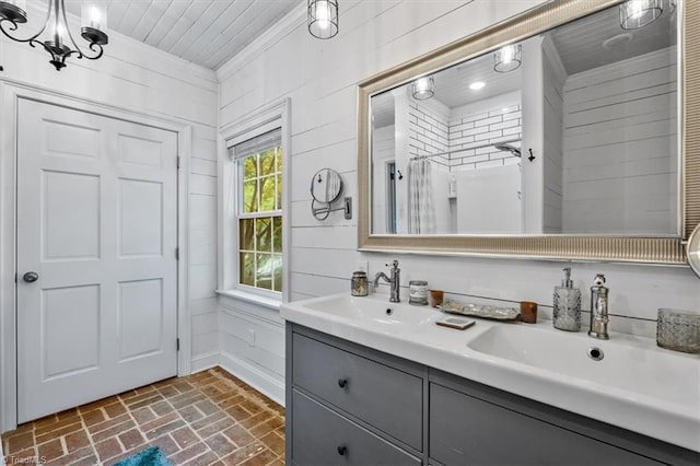 bathroom with brick flooring, a chandelier, double vanity, baseboards, and crown molding