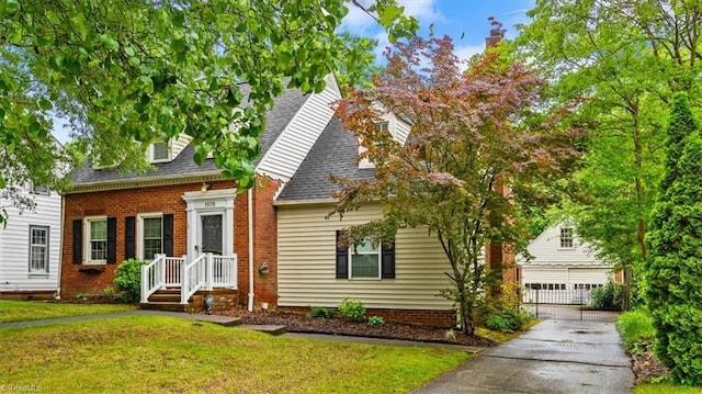 cape cod home featuring a front yard, a shingled roof, a garage, and brick siding