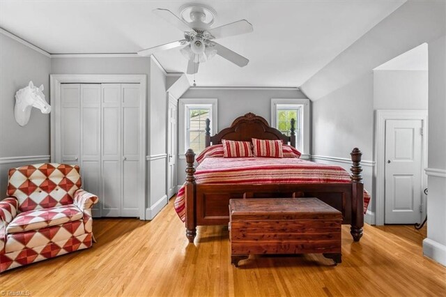 bedroom with a closet, light wood-type flooring, lofted ceiling, ceiling fan, and baseboards