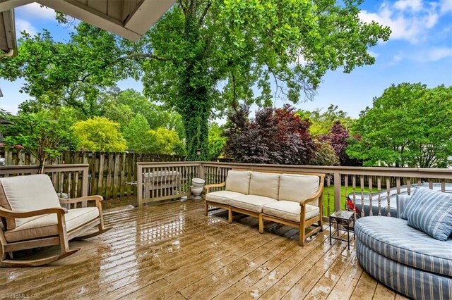 wooden deck with an outdoor living space and fence