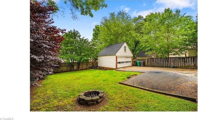 view of yard featuring a garage, an outbuilding, and a fire pit