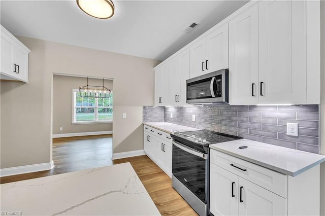 1333 Union Cross Rd, Kernersville, NC 27284 - kitchen with appliances with stainless steel finishes, light wood-type flooring, decorative backsplash, light stone countertops, and white cabinetry