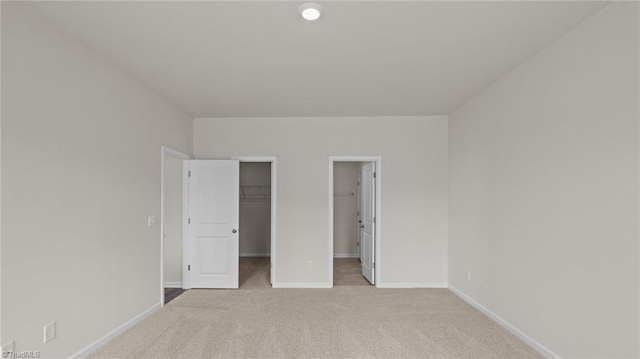 unfurnished bedroom featuring baseboards, carpet, a closet, and a walk in closet