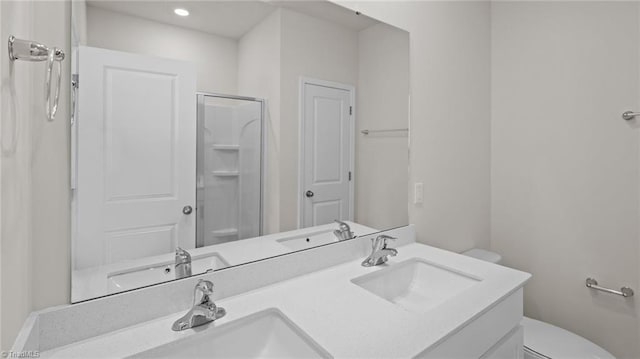 full bathroom featuring double vanity, a sink, a stall shower, and toilet
