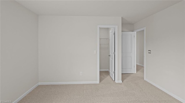 unfurnished bedroom featuring carpet floors, baseboards, a closet, and a walk in closet