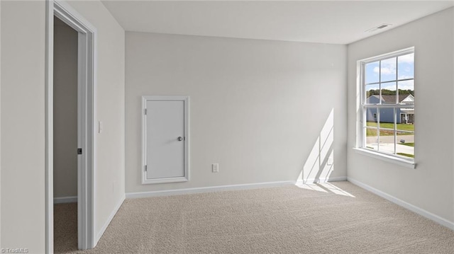 empty room featuring visible vents, carpet, baseboards, and a wealth of natural light