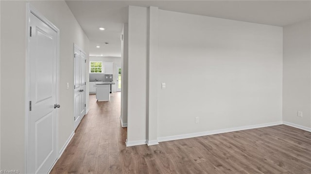 corridor with baseboards, recessed lighting, and wood finished floors