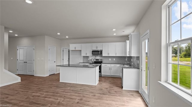 kitchen featuring white cabinets, stainless steel appliances, a sink, and a center island