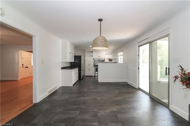 kitchen featuring hanging light fixtures, white cabinetry, stainless steel refrigerator, tasteful backsplash, and ornamental molding