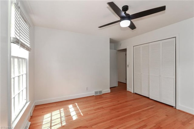 unfurnished bedroom featuring multiple windows, ceiling fan, a closet, and light hardwood / wood-style flooring