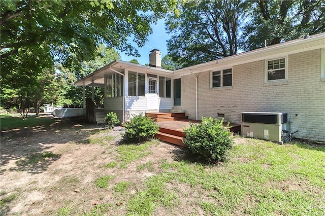 rear view of property featuring a yard, a sunroom, and a deck