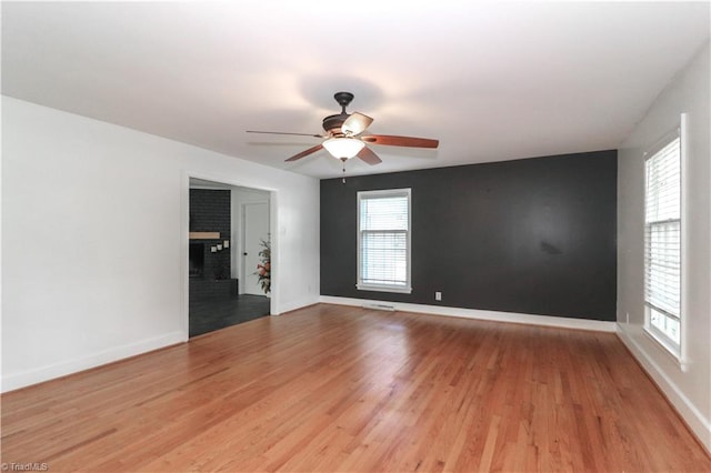 unfurnished living room featuring ceiling fan, a fireplace, and light hardwood / wood-style floors