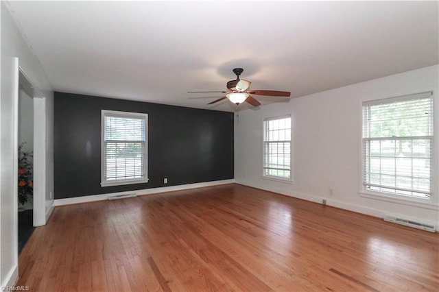 spare room with ceiling fan, a wealth of natural light, and light hardwood / wood-style flooring