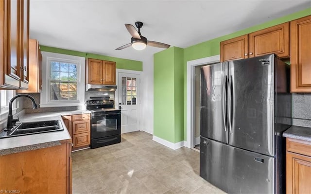 kitchen with freestanding refrigerator, a ceiling fan, black electric range oven, under cabinet range hood, and a sink