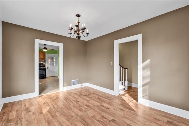 spare room featuring visible vents, baseboards, light wood-style floors, stairway, and ceiling fan with notable chandelier