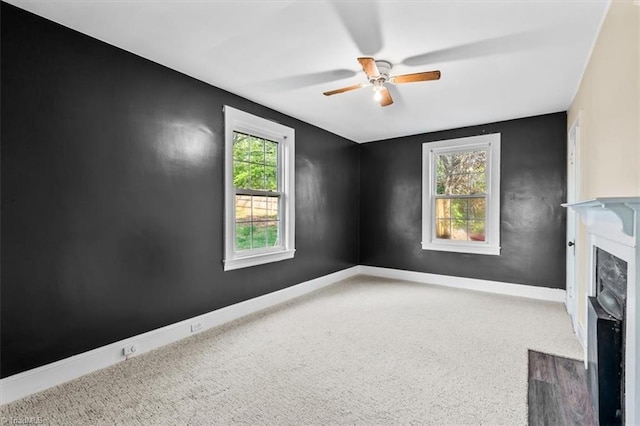 unfurnished living room with baseboards, a ceiling fan, carpet flooring, and a premium fireplace