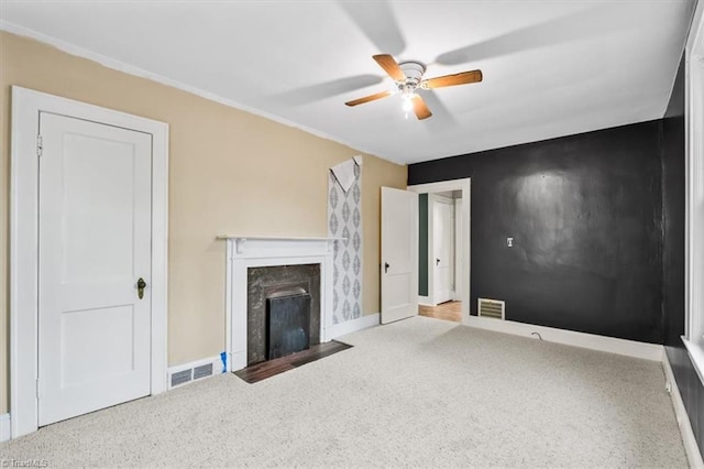 unfurnished living room with baseboards, visible vents, ceiling fan, a high end fireplace, and carpet