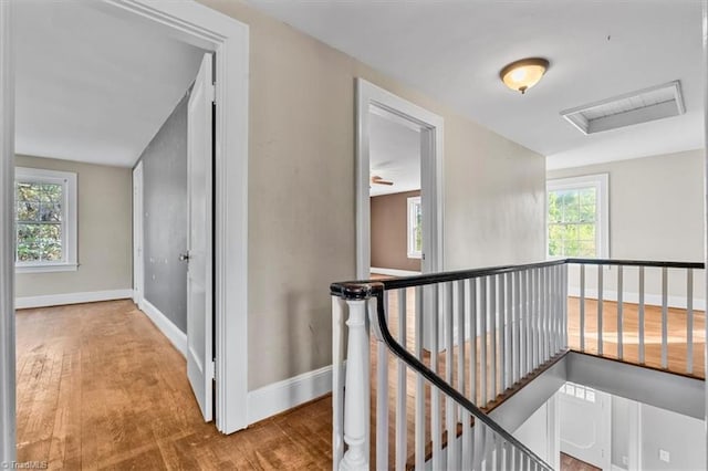 hall featuring baseboards, an upstairs landing, and wood finished floors