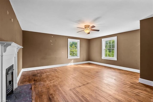 unfurnished living room with ceiling fan, baseboards, wood finished floors, and a fireplace