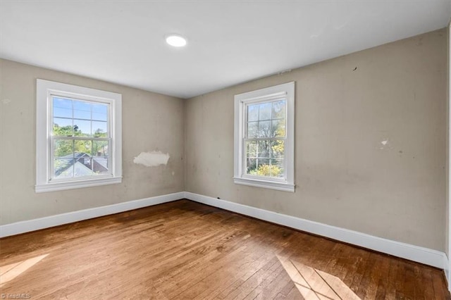 unfurnished room with baseboards, plenty of natural light, and hardwood / wood-style flooring