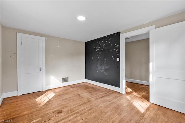 spare room featuring recessed lighting, visible vents, baseboards, and wood finished floors